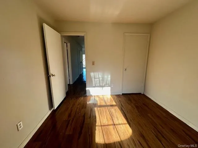 Unfurnished bedroom featuring dark wood finished floors Unfurnished bedroom featuring dark wood finished floors