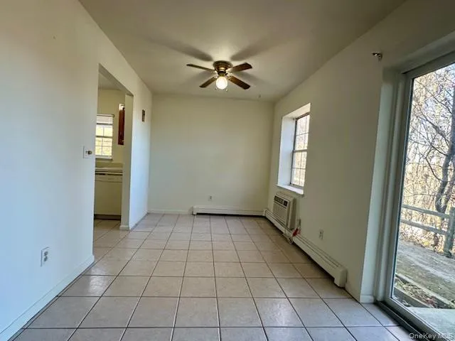Unfurnished room featuring light tile patterned floors, ceiling fan, and baseboard heating Unfurnished room featuring light tile patterned floors, ceiling fan, and baseboard heating