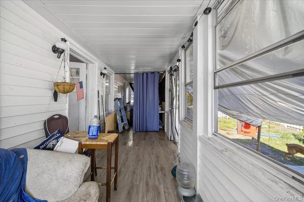 Sunroom / solarium with wood finished floors, healthy amount of natural light, a barn door, and wooden walls Sunroom / solarium with wood finished floors, healthy amount of natural light, a barn door, and wooden walls