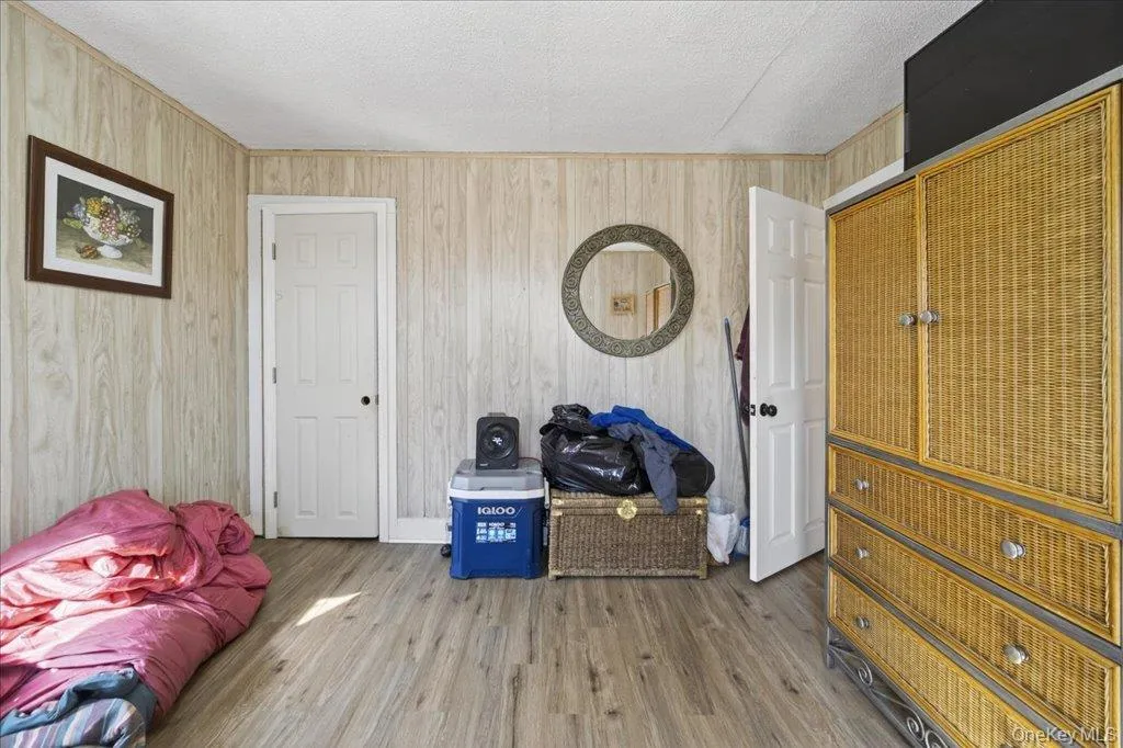 Bedroom featuring wood finished floors, a textured ceiling, and wooden walls Bedroom featuring wood finished floors, a textured ceiling, and wooden walls