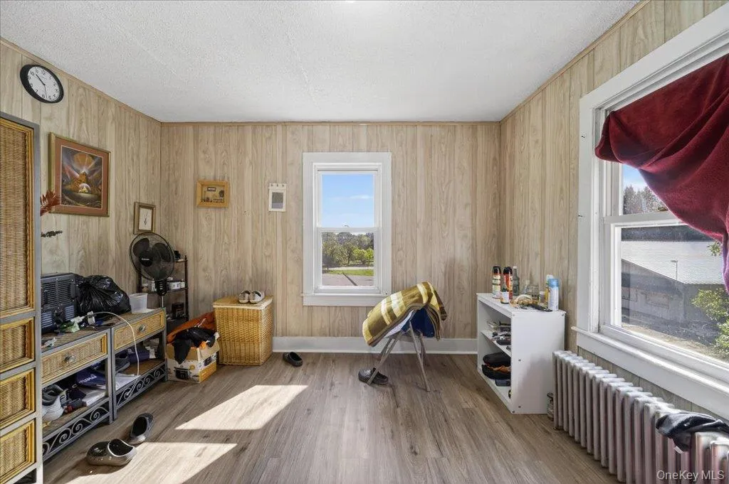 Office area with radiator, wood finished floors, and wood walls Office area with radiator, wood finished floors, and wood walls