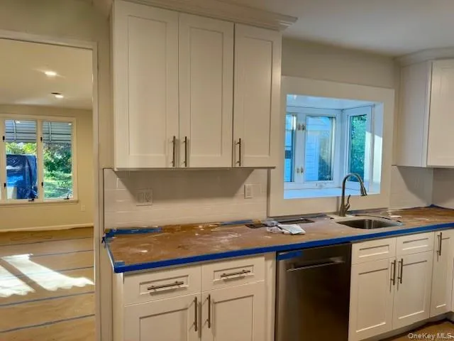 Kitchen with dishwasher, white cabinets, and decorative backsplash Kitchen with dishwasher, white cabinets, and decorative backsplash