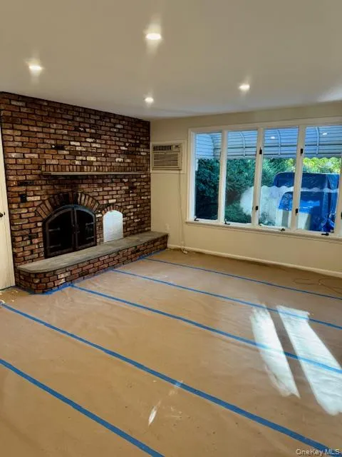 Unfurnished living room with a fireplace, a wall unit AC, and recessed lighting Unfurnished living room with a fireplace, a wall unit AC, and recessed lighting