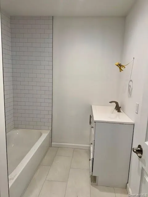 Bathroom featuring vanity, light tile patterned flooring, and washtub / shower combination Bathroom featuring vanity, light tile patterned flooring, and washtub / shower combination