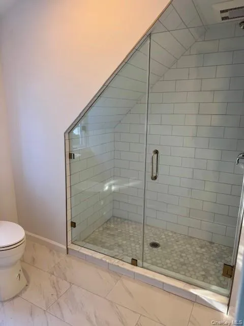 Bathroom featuring a stall shower and light marble finish floors Bathroom featuring a stall shower and light marble finish floors