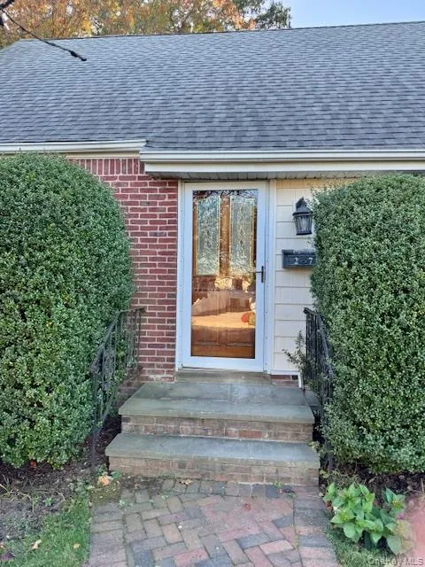 Doorway to property with roof with shingles and brick siding Doorway to property with roof with shingles and brick siding