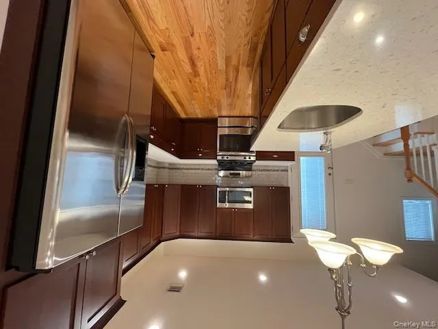 Kitchen featuring white fridge, hanging light fixtures, stainless steel range oven, light wood finished floors, and decorative backsplash Kitchen featuring white fridge, hanging light fixtures, stainless steel range oven, light wood finished floors, and decorative backsplash