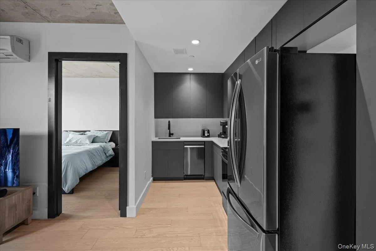 Kitchen featuring refrigerator with ice dispenser, modern cabinets, light wood-type flooring, recessed lighting, and stainless steel dishwasher Kitchen featuring refrigerator with ice dispenser, modern cabinets, light wood-type flooring, recessed lighting, and stainless steel dishwasher