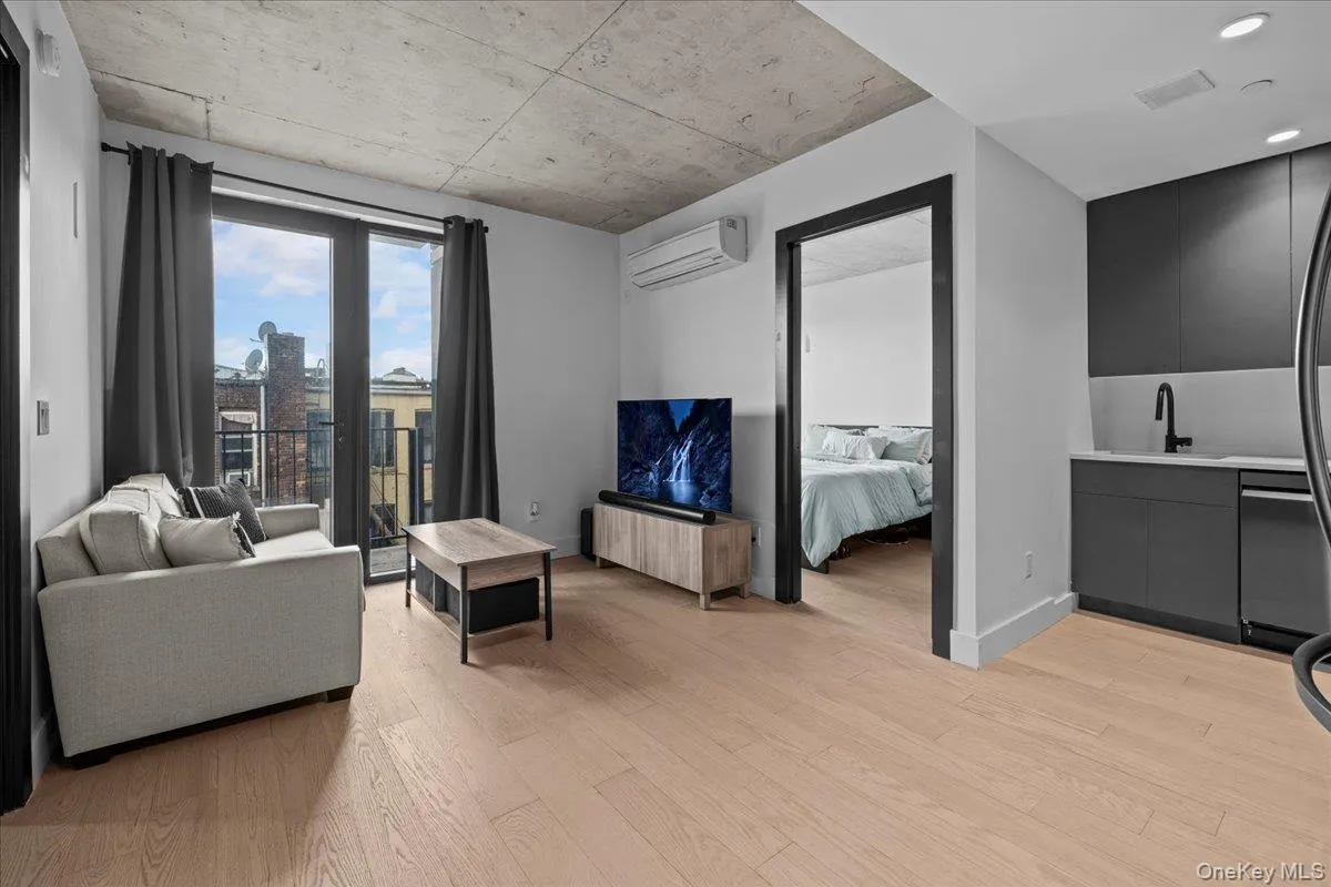 Living room with light wood-style floors and a wall mounted air conditioner Living room with light wood-style floors and a wall mounted air conditioner