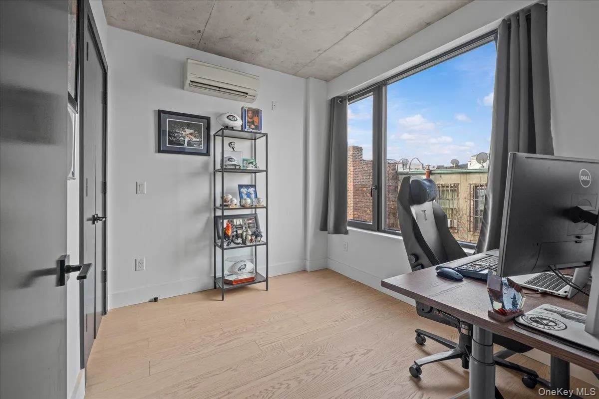 Office space with light wood-style floors and a wall mounted air conditioner Office space with light wood-style floors and a wall mounted air conditioner
