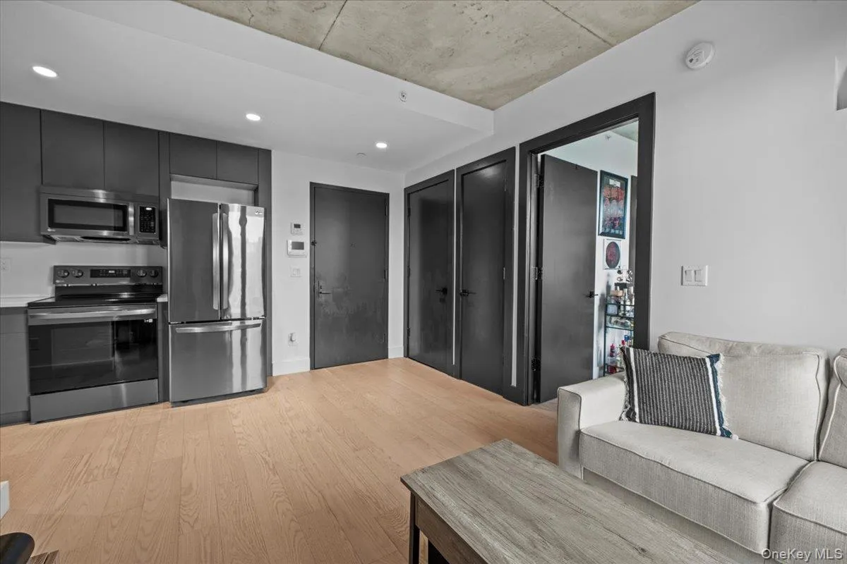 Kitchen featuring stainless steel appliances, light wood-style floors, light countertops, dark cabinets, and recessed lighting Kitchen featuring stainless steel appliances, light wood-style floors, light countertops, dark cabinets, and recessed lighting