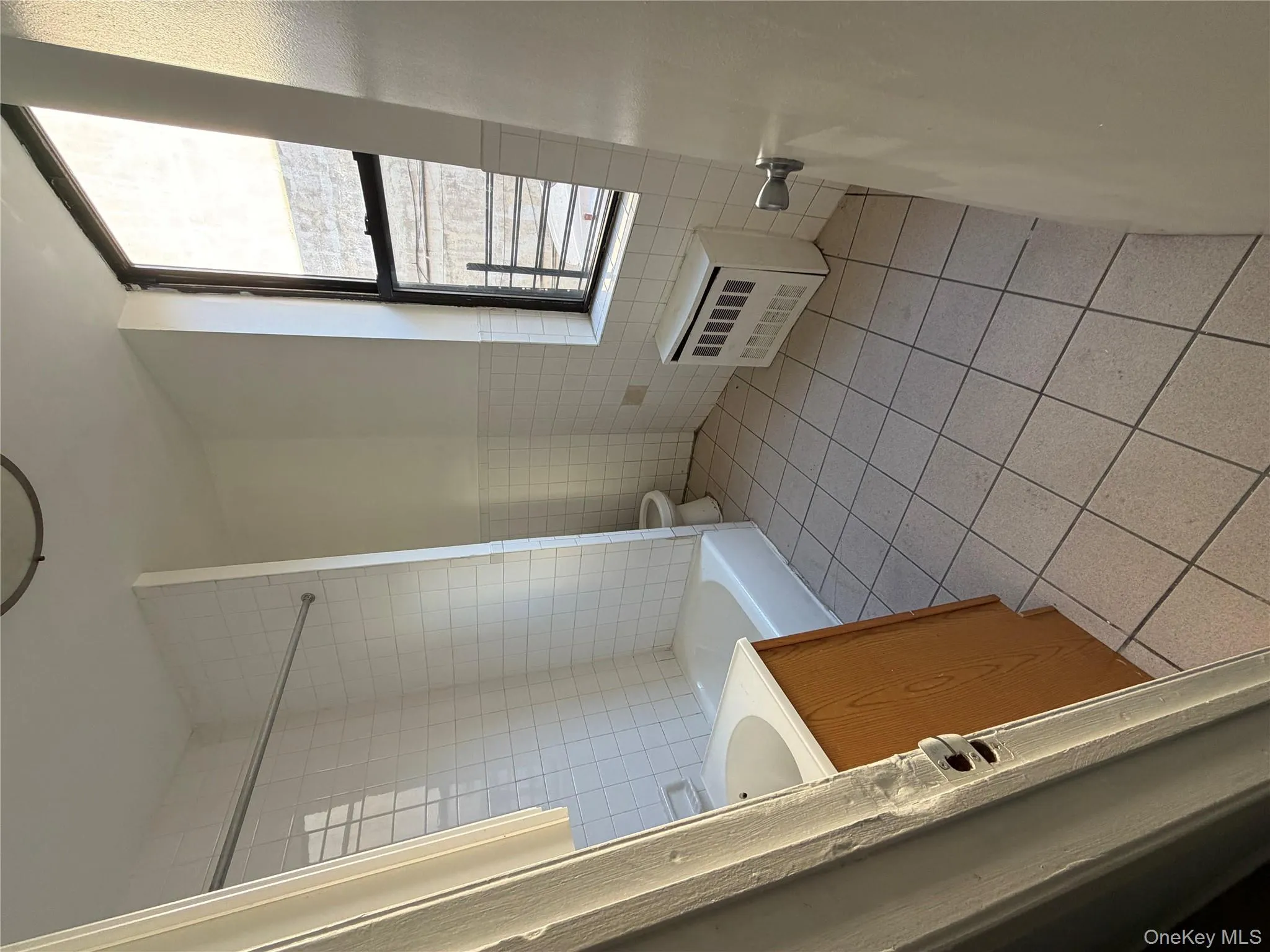 Full bathroom with light tile patterned floors, vanity, tile walls, tub / shower combination, and radiator heating unit Full bathroom with light tile patterned floors, vanity, tile walls, tub / shower combination, and radiator heating unit