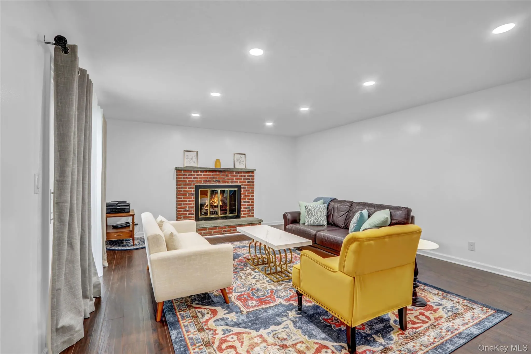 Living room featuring recessed lighting, dark wood-style flooring, and a fireplace Living room featuring recessed lighting, dark wood-style flooring, and a fireplace