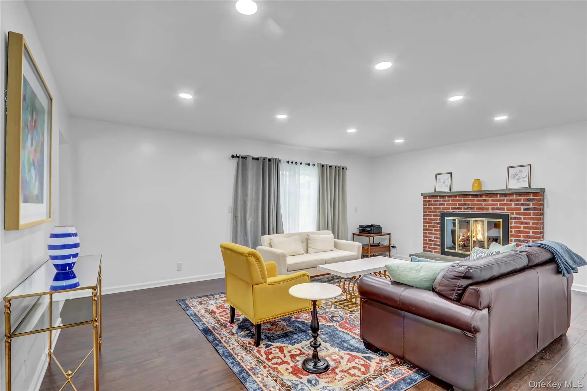 Living area featuring dark wood finished floors, a brick fireplace, and recessed lighting Living area featuring dark wood finished floors, a brick fireplace, and recessed lighting
