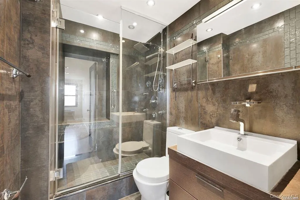 Full bathroom with vanity, a shower stall, tile walls, and recessed lighting Full bathroom with vanity, a shower stall, tile walls, and recessed lighting
