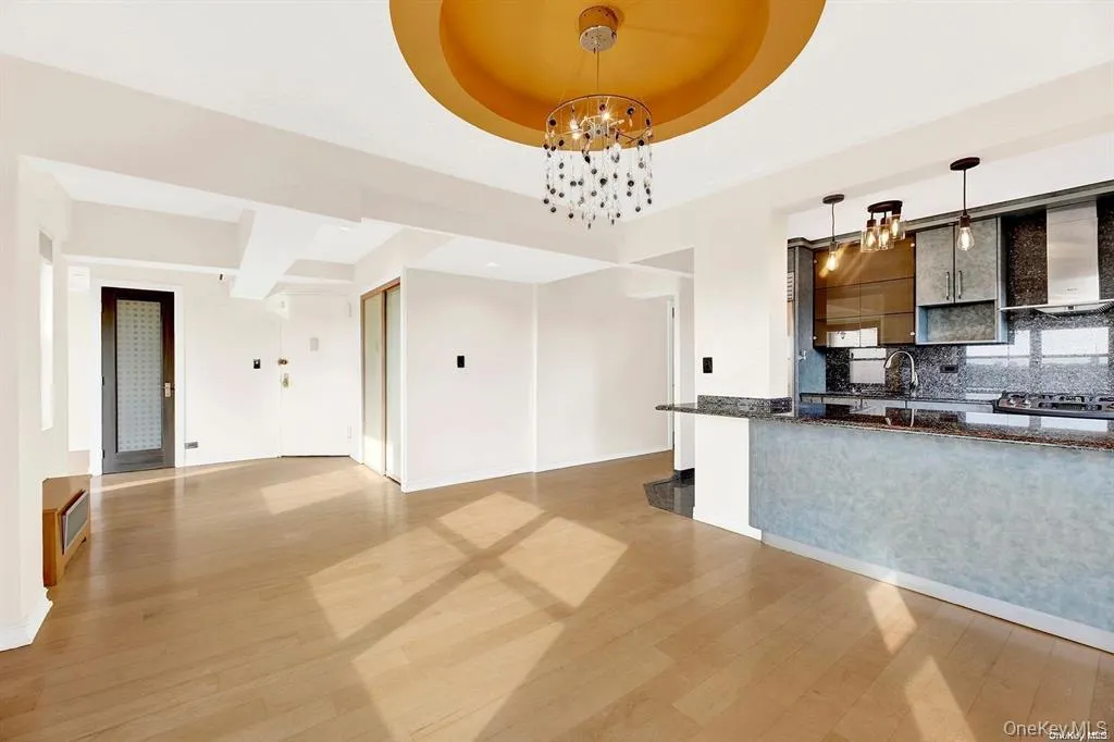 Kitchen with tasteful backsplash, pendant lighting, wall chimney exhaust hood, open floor plan, and dark stone counters Kitchen with tasteful backsplash, pendant lighting, wall chimney exhaust hood, open floor plan, and dark stone counters