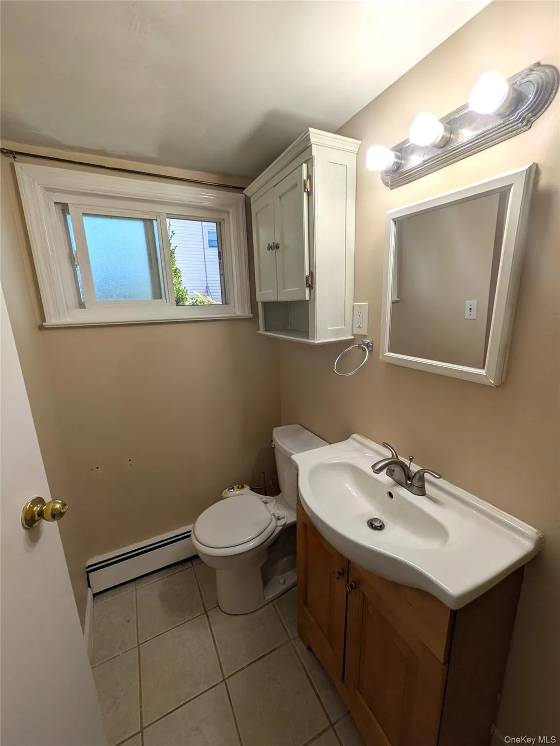 bath with a baseboard heating unit, vanity, and light tile patterned flooring bath with a baseboard heating unit, vanity, and light tile patterned flooring