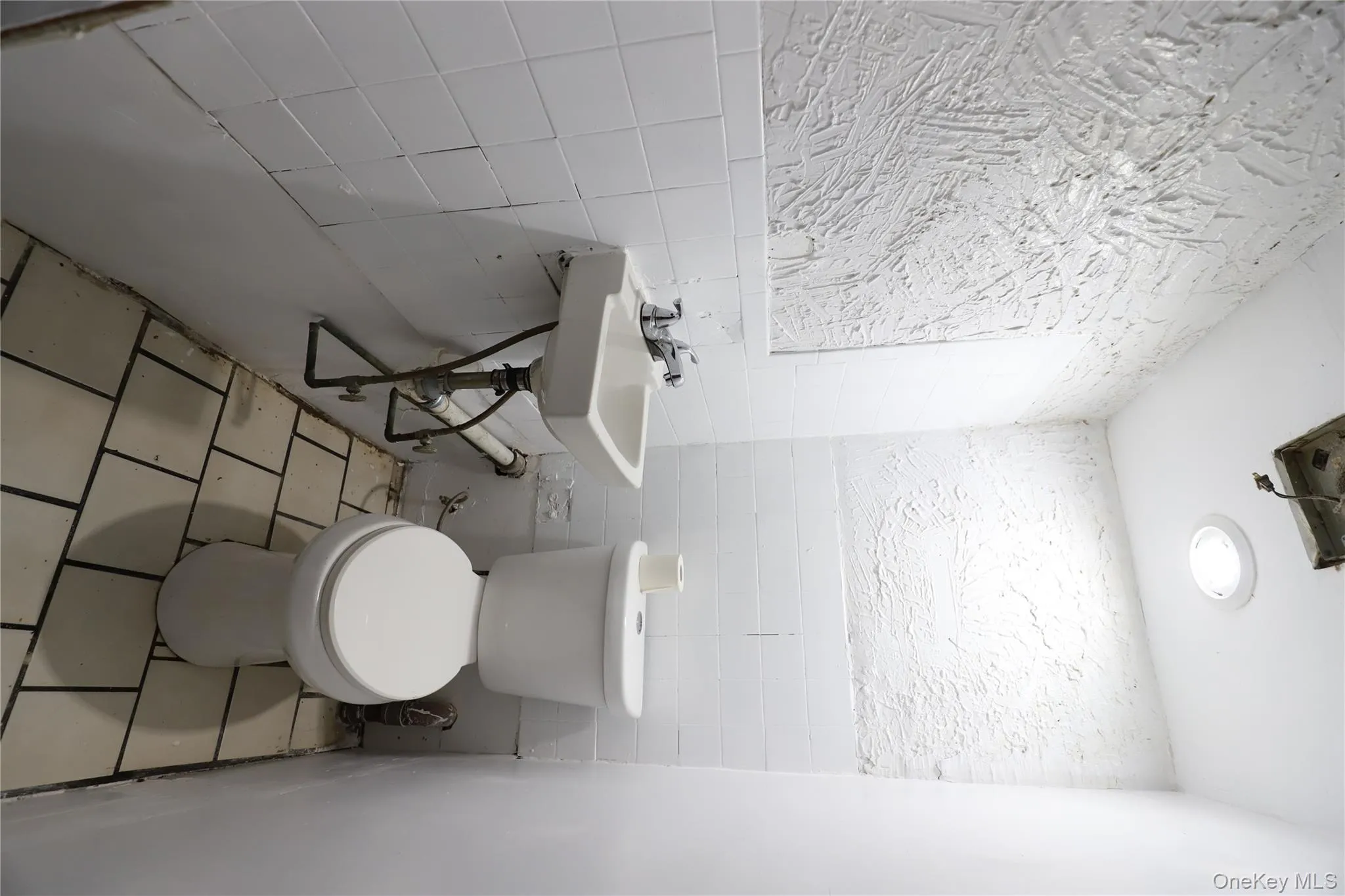 Bathroom with tile walls, light tile patterned floors, and wainscoting Bathroom with tile walls, light tile patterned floors, and wainscoting