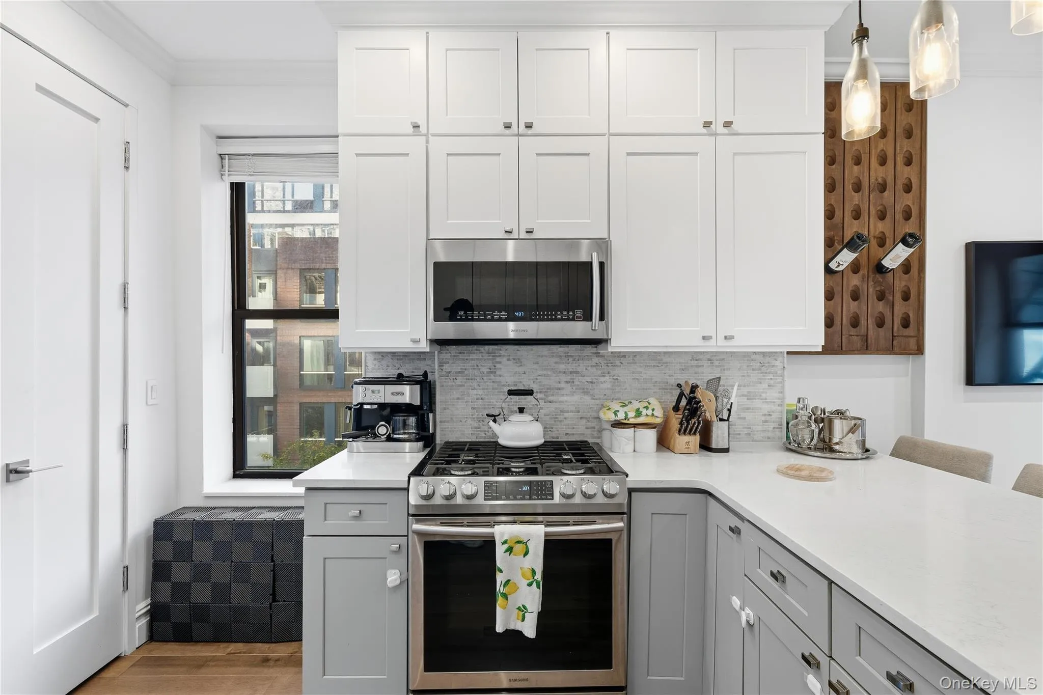 Kitchen with stainless steel appliances, white cabinetry, gray cabinetry, tasteful backsplash, and light stone countertops Kitchen with stainless steel appliances, white cabinetry, gray cabinetry, tasteful backsplash, and light stone countertops