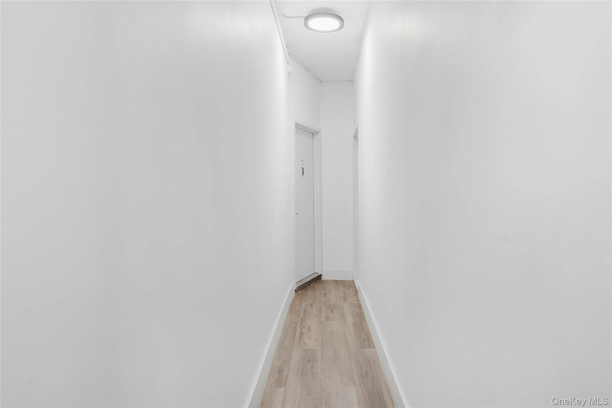Corridor with light wood-style flooring and baseboards Corridor with light wood-style flooring and baseboards