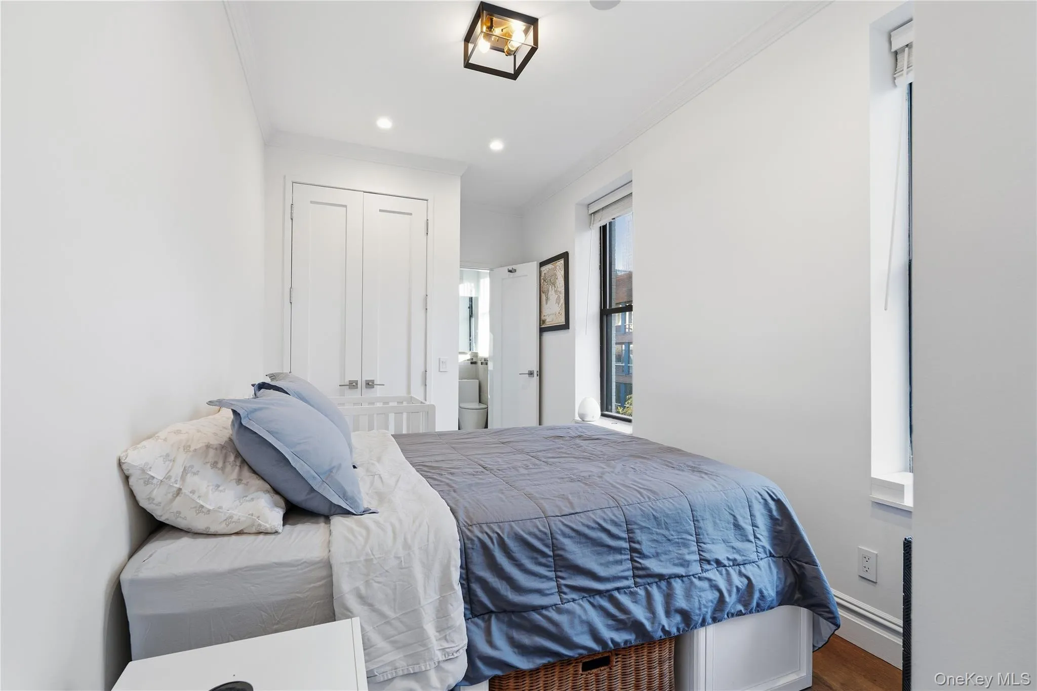Bedroom with ornamental molding, wood finished floors, recessed lighting, and a closet Bedroom with ornamental molding, wood finished floors, recessed lighting, and a closet