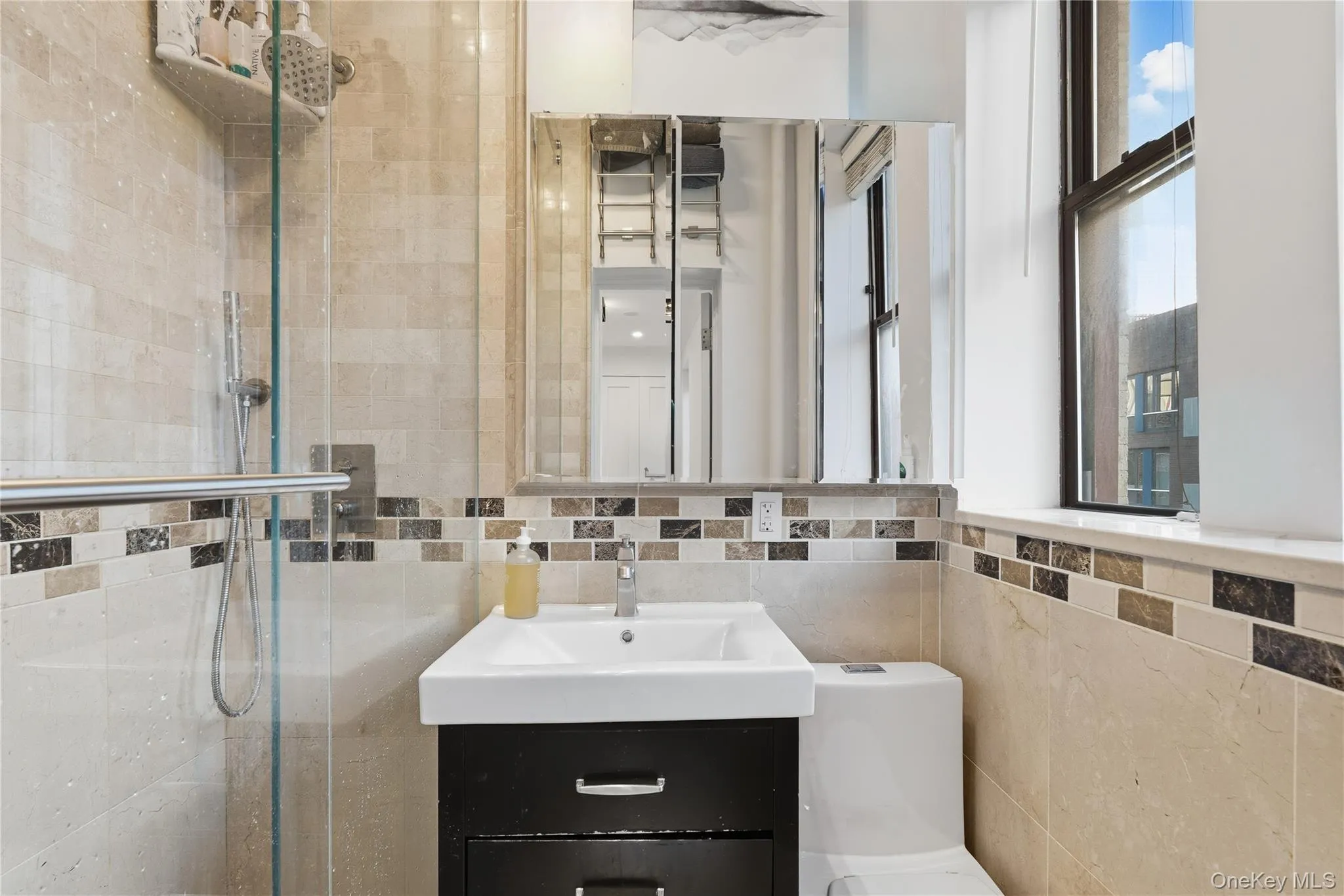 Bathroom with a shower stall, tile walls, vanity, and tasteful backsplash Bathroom with a shower stall, tile walls, vanity, and tasteful backsplash