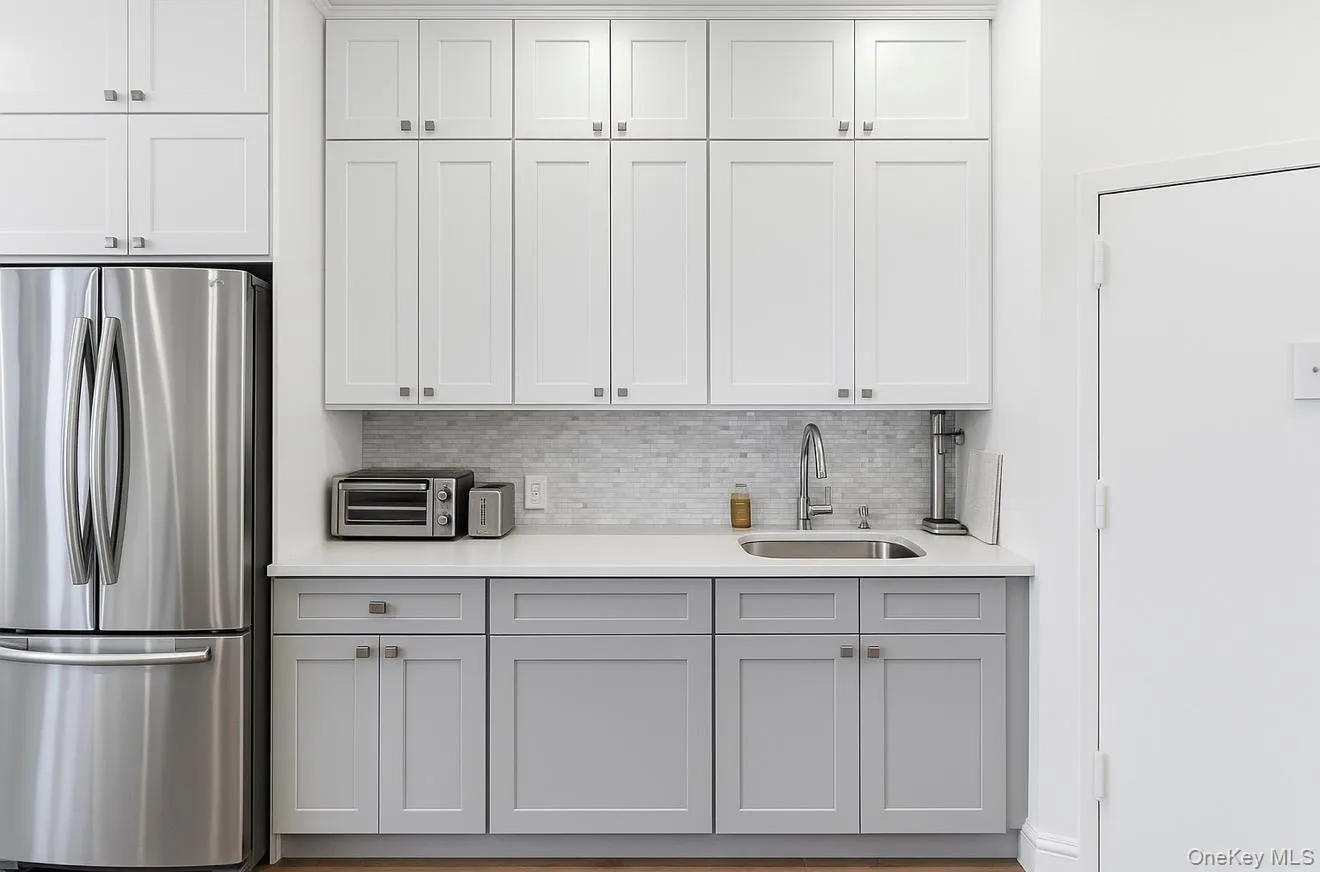 Kitchen with freestanding refrigerator, tasteful backsplash, white cabinets, and gray cabinets Kitchen with freestanding refrigerator, tasteful backsplash, white cabinets, and gray cabinets