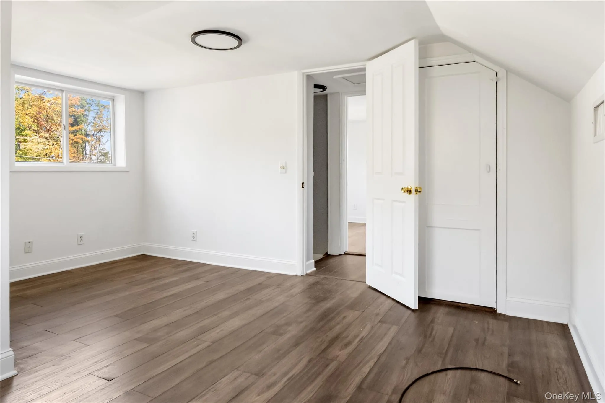 Unfurnished bedroom with dark wood-style flooring and baseboards Unfurnished bedroom with dark wood-style flooring and baseboards