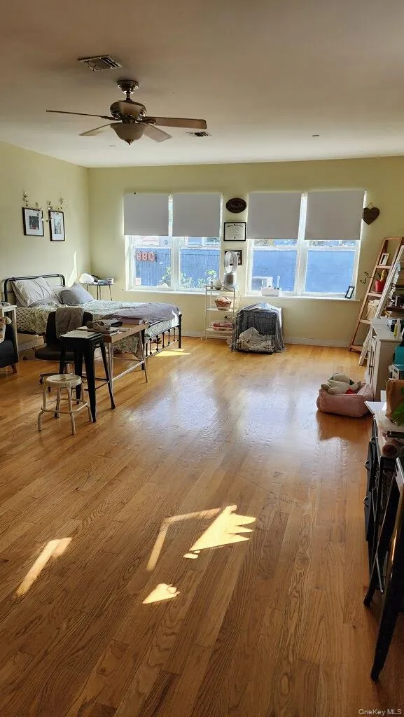 Bedroom with light wood-type flooring, multiple windows, and a ceiling fan Bedroom with light wood-type flooring, multiple windows, and a ceiling fan