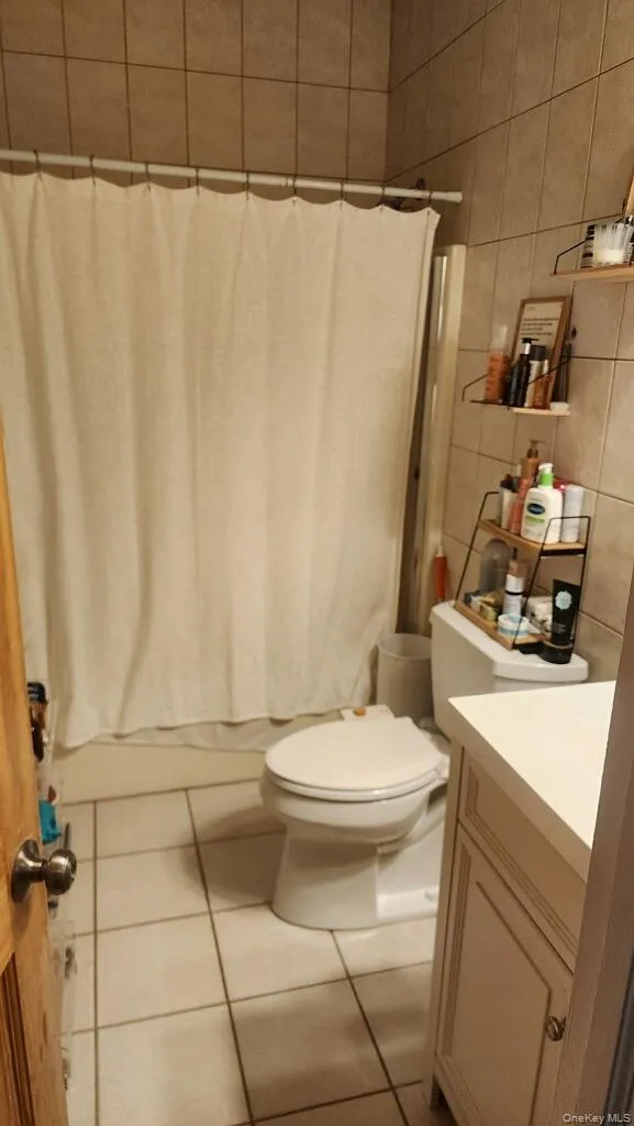 Full bath featuring tile patterned floors, tile walls, and vanity Full bath featuring tile patterned floors, tile walls, and vanity