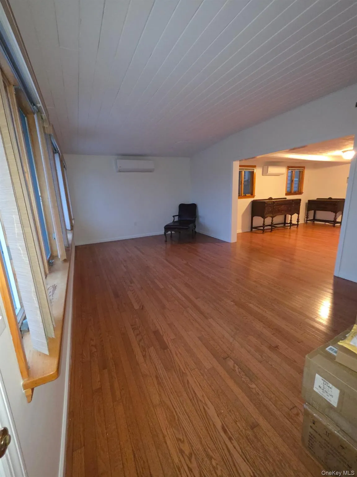 Unfurnished living room featuring light wood finished floors, a wall mounted AC, and an AC wall unit Unfurnished living room featuring light wood finished floors, a wall mounted AC, and an AC wall unit