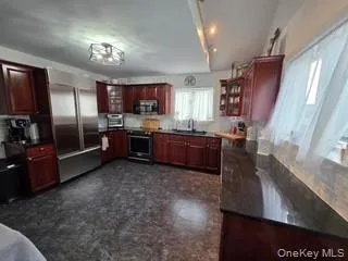 Kitchen with glass insert cabinets, dark brown cabinets, stainless steel appliances, tasteful backsplash, and dark stone counters Kitchen with glass insert cabinets, dark brown cabinets, stainless steel appliances, tasteful backsplash, and dark stone counters