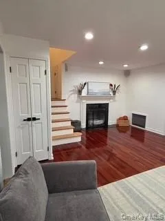 Living room featuring dark wood-style floors, a glass covered fireplace, and recessed lighting Living room featuring dark wood-style floors, a glass covered fireplace, and recessed lighting