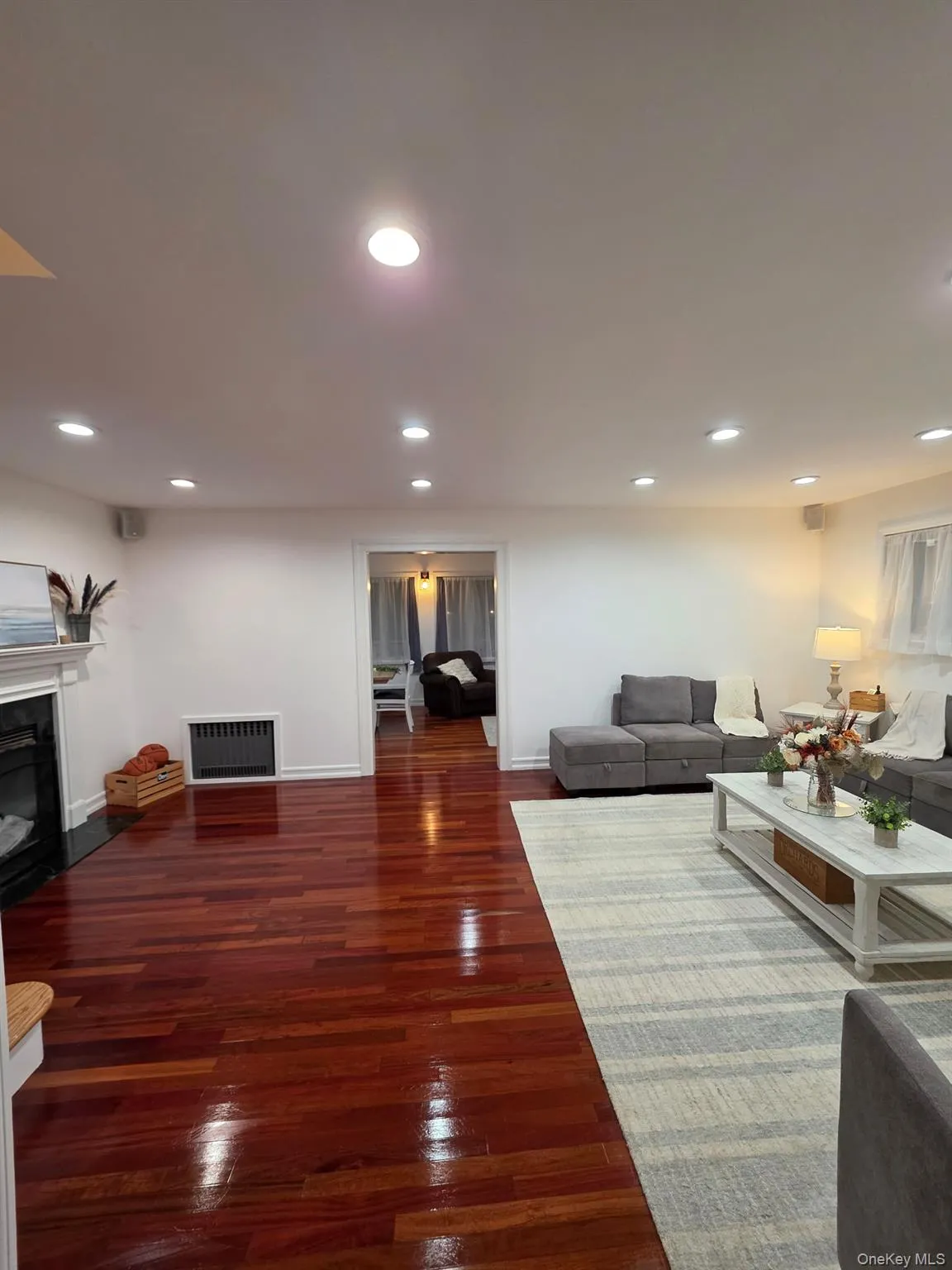 Living room with a glass covered fireplace, dark wood-type flooring, recessed lighting, and heating unit Living room with a glass covered fireplace, dark wood-type flooring, recessed lighting, and heating unit