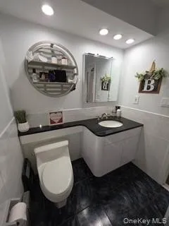 Bathroom featuring tile walls, a wainscoted wall, vanity, recessed lighting, and radiator Bathroom featuring tile walls, a wainscoted wall, vanity, recessed lighting, and radiator