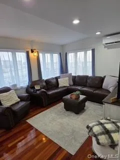Living room featuring dark wood finished floors, recessed lighting, and a wall mounted air conditioner Living room featuring dark wood finished floors, recessed lighting, and a wall mounted air conditioner