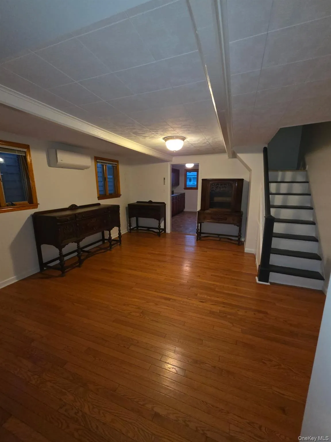 Finished basement featuring hardwood / wood-style floors, stairway, and a wall mounted air conditioner Finished basement featuring hardwood / wood-style floors, stairway, and a wall mounted air conditioner
