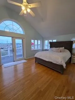 Bedroom with multiple windows, wood finished floors, ceiling fan, and high vaulted ceiling Bedroom with multiple windows, wood finished floors, ceiling fan, and high vaulted ceiling