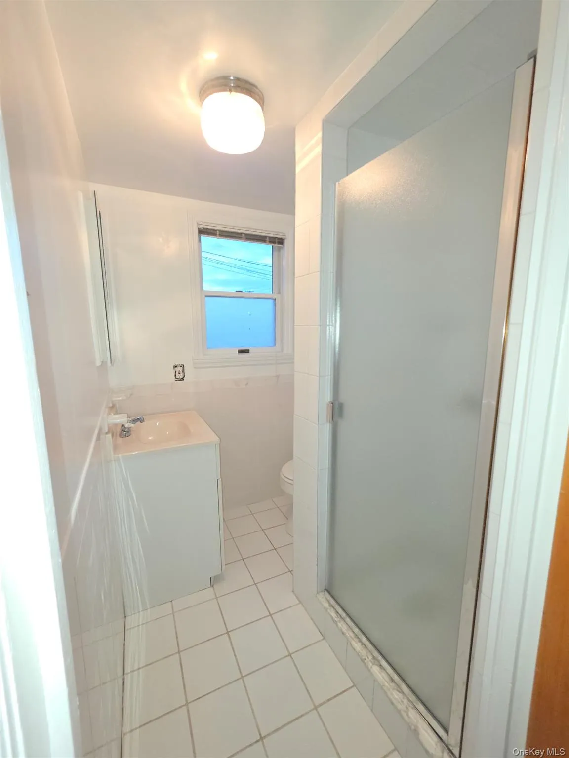 Bathroom with vanity, light tile patterned floors, a shower stall, and tile walls Bathroom with vanity, light tile patterned floors, a shower stall, and tile walls