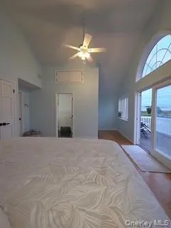 Bedroom featuring high vaulted ceiling, dark wood-style floors, access to exterior, and a ceiling fan Bedroom featuring high vaulted ceiling, dark wood-style floors, access to exterior, and a ceiling fan