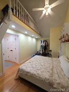 Bedroom featuring wood finished floors, a high ceiling, a ceiling fan, and recessed lighting Bedroom featuring wood finished floors, a high ceiling, a ceiling fan, and recessed lighting