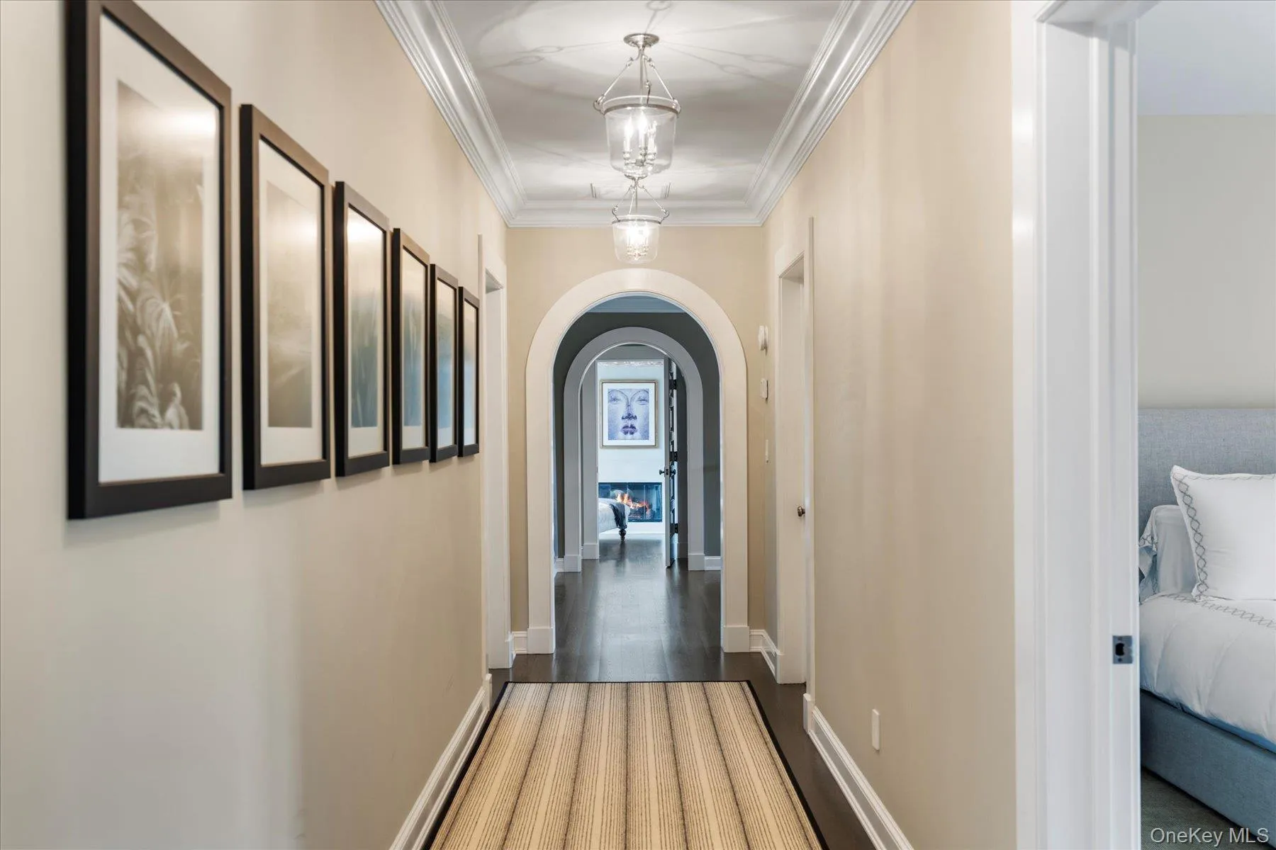 Corridor featuring arched walkways, crown molding, and wood finished floors Corridor featuring arched walkways, crown molding, and wood finished floors