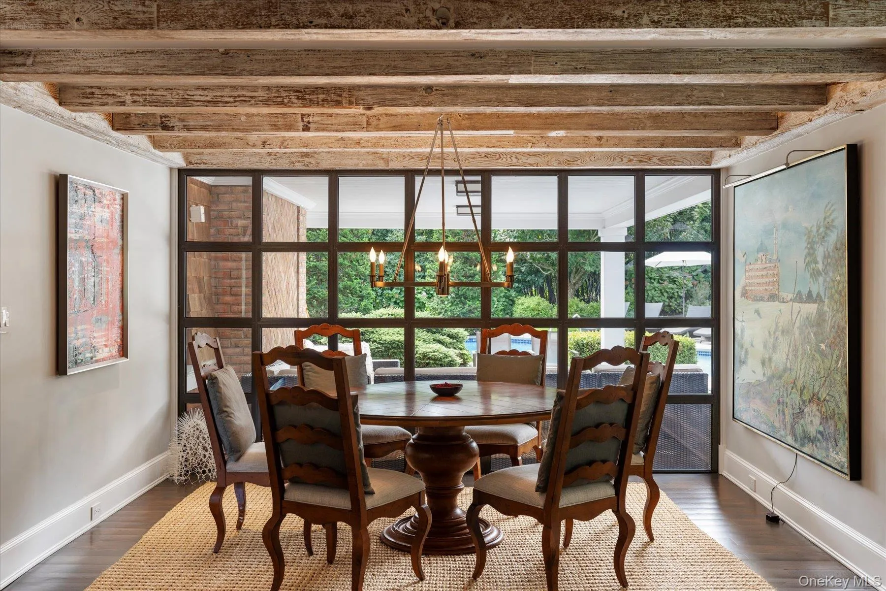 Dining space with dark wood-style flooring, beam ceiling, a chandelier, and a wall of windows Dining space with dark wood-style flooring, beam ceiling, a chandelier, and a wall of windows