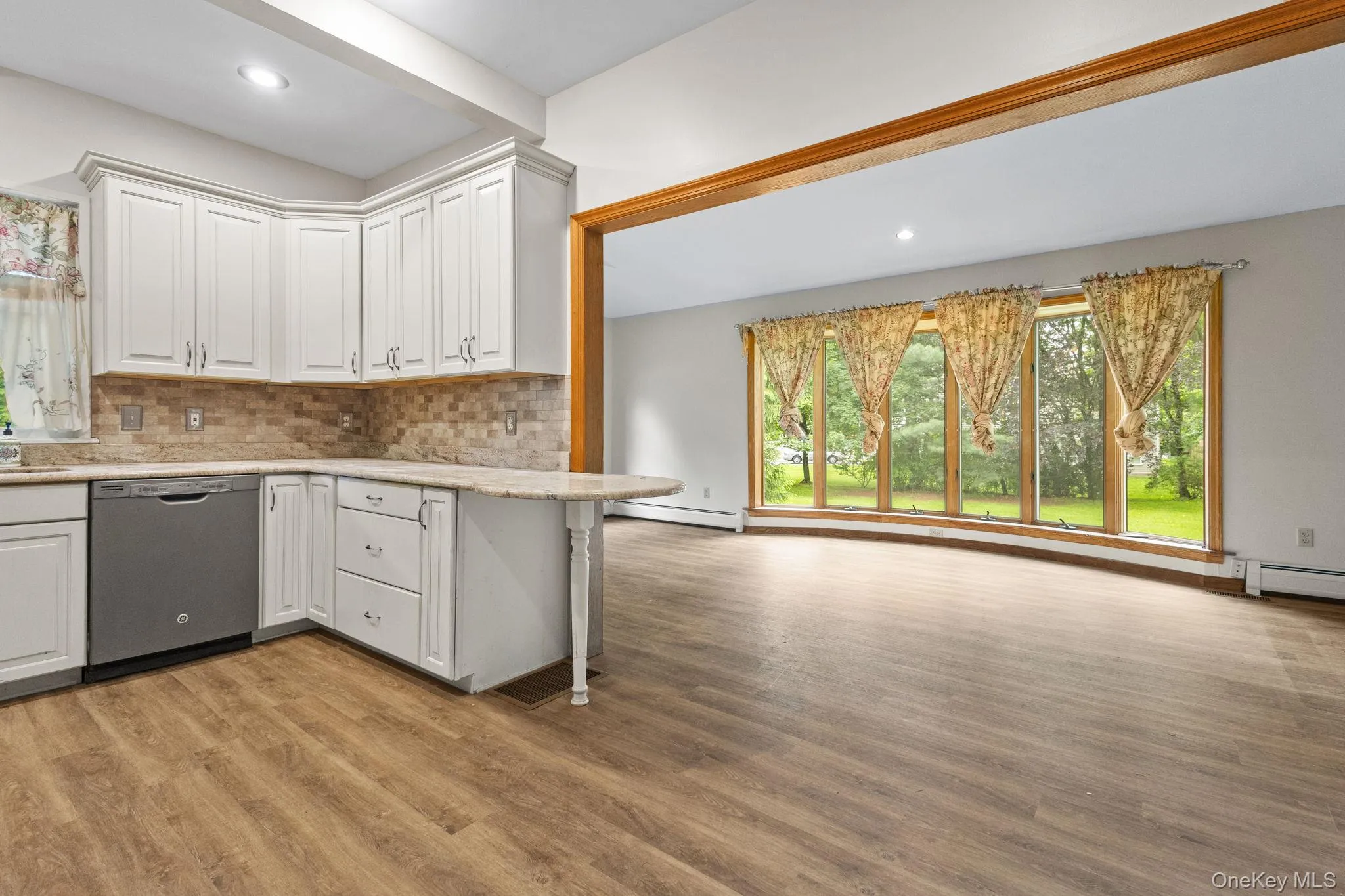 Kitchen featuring dishwasher, light wood finished floors, tasteful backsplash, white cabinets, and recessed lighting Kitchen featuring dishwasher, light wood finished floors, tasteful backsplash, white cabinets, and recessed lighting