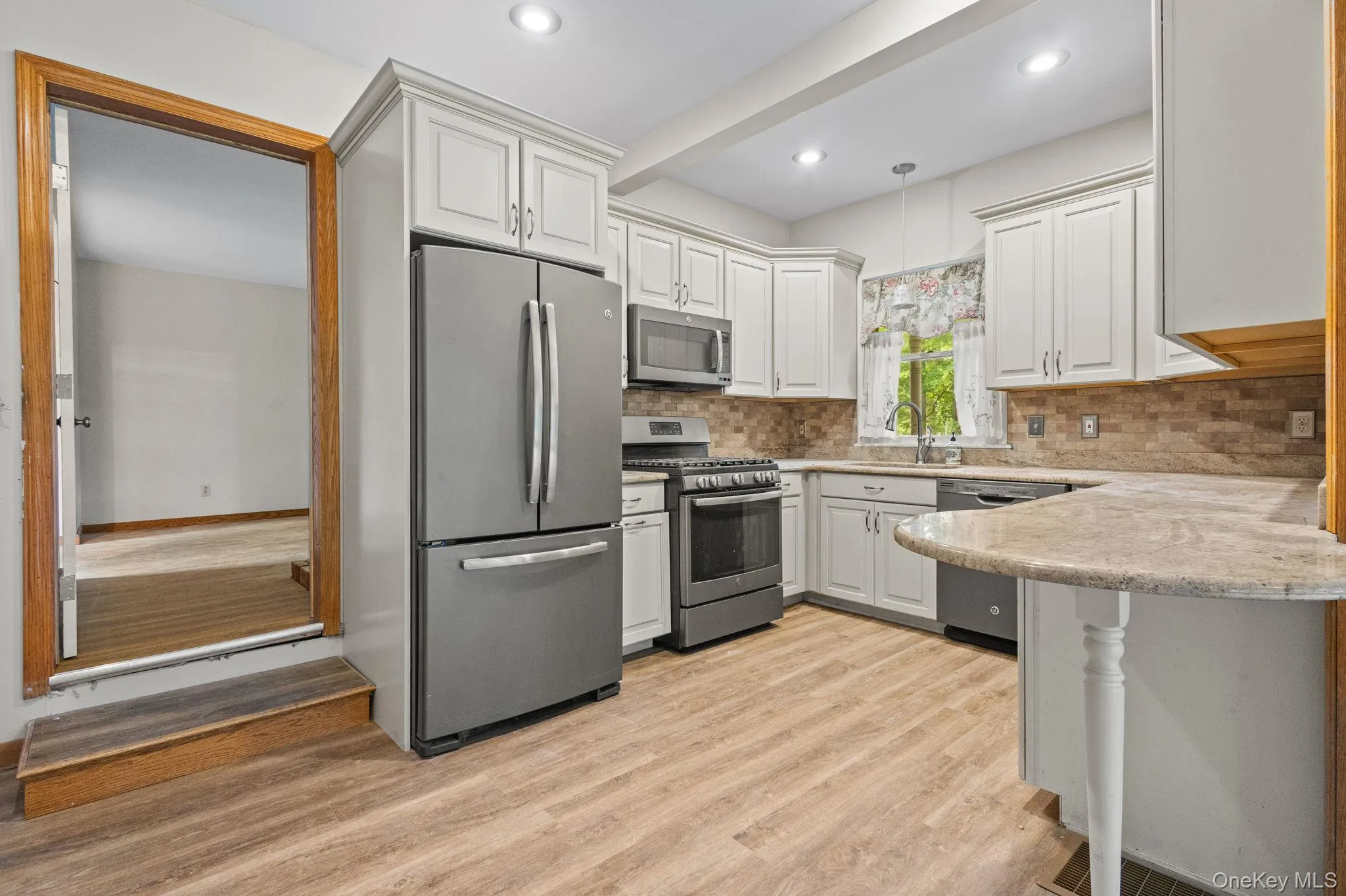 Kitchen featuring stainless steel appliances, a sink, light wood finished floors, decorative backsplash, and recessed lighting Kitchen featuring stainless steel appliances, a sink, light wood finished floors, decorative backsplash, and recessed lighting