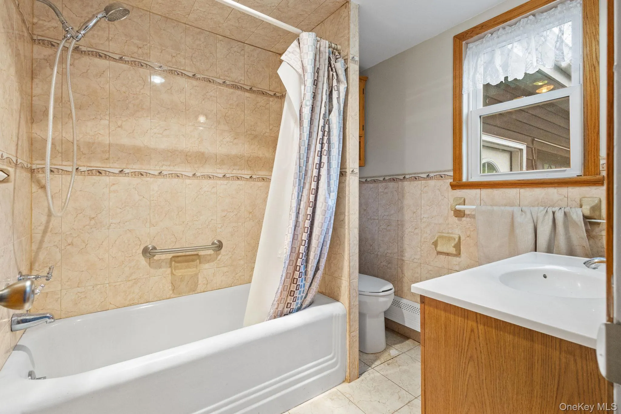 Bathroom featuring toilet, vanity, and shower / bath combination with curtain Bathroom featuring toilet, vanity, and shower / bath combination with curtain