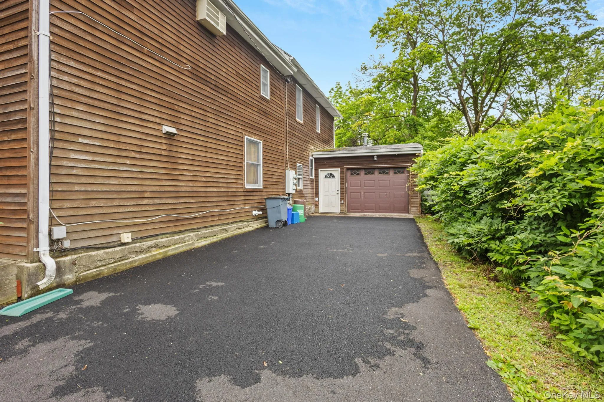 View of side of home featuring an outdoor structure, a garage, and driveway View of side of home featuring an outdoor structure, a garage, and driveway