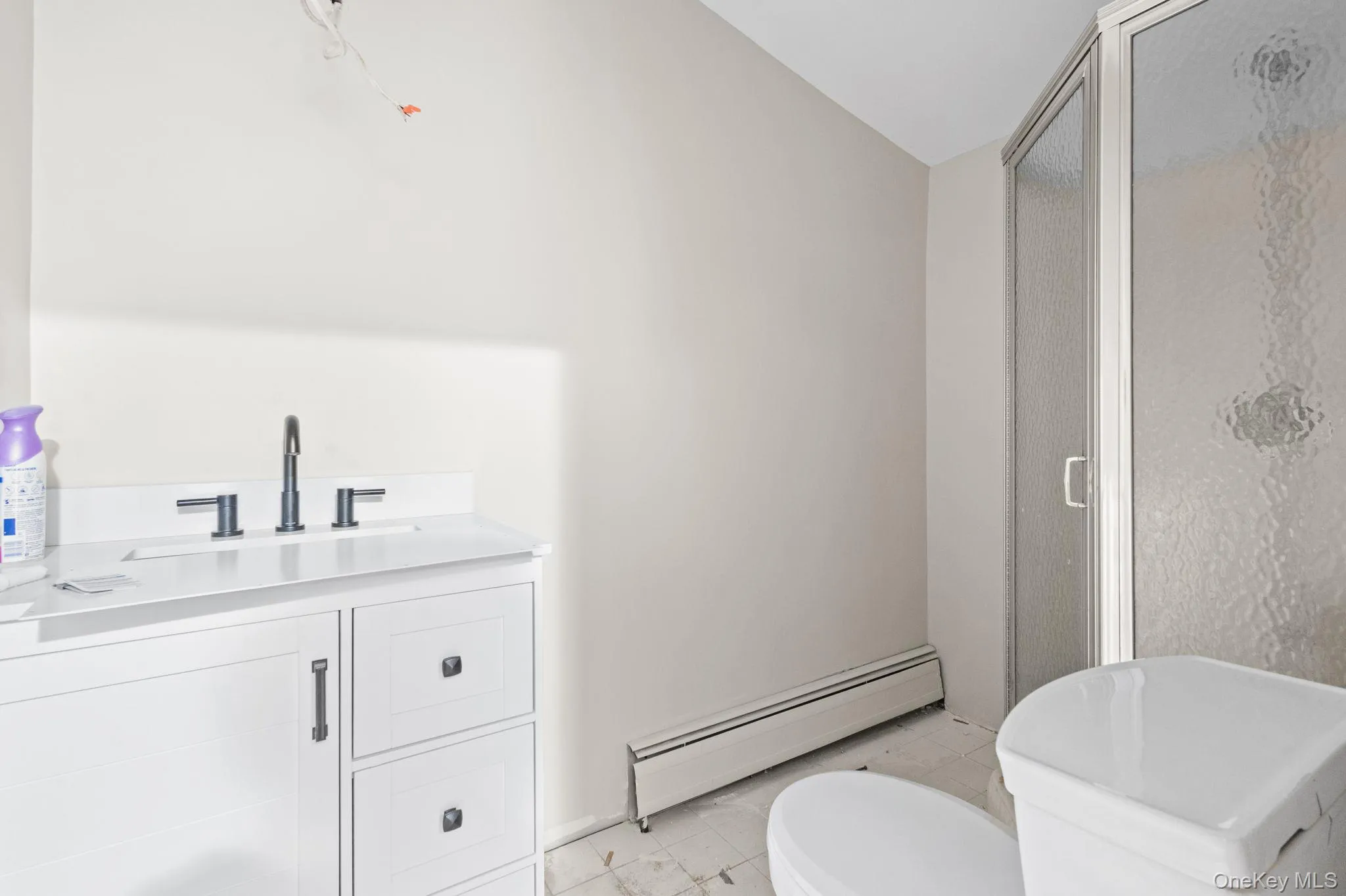 Full bathroom featuring baseboard heating, toilet, a shower stall, marble look tile flooring, and vaulted ceiling Full bathroom featuring baseboard heating, toilet, a shower stall, marble look tile flooring, and vaulted ceiling