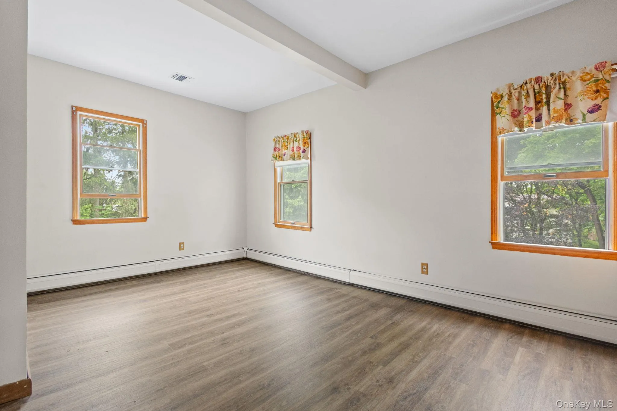 Unfurnished room with wood finished floors and beam ceiling Unfurnished room with wood finished floors and beam ceiling