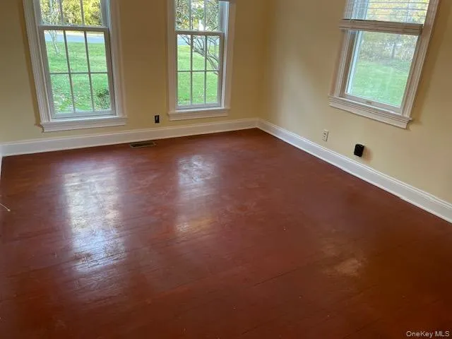 Unfurnished room with baseboards and dark wood-style floors Unfurnished room with baseboards and dark wood-style floors